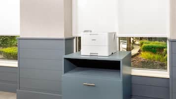 A printer on a grey cabinet with a window view of a garden.