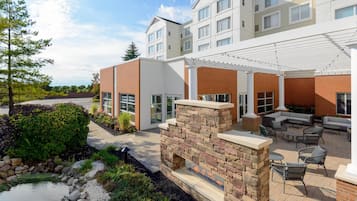 A modern building with a patio area featuring outdoor seating and a fire pit.