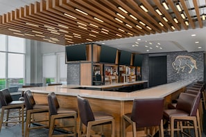 Un área de bar moderna con una barra larga, taburetes y una pared con un diseño de luz de neón.