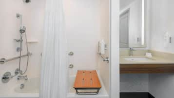 Une salle de bain moderne avec une douche, un banc en bois et un lavabo avec un miroir.