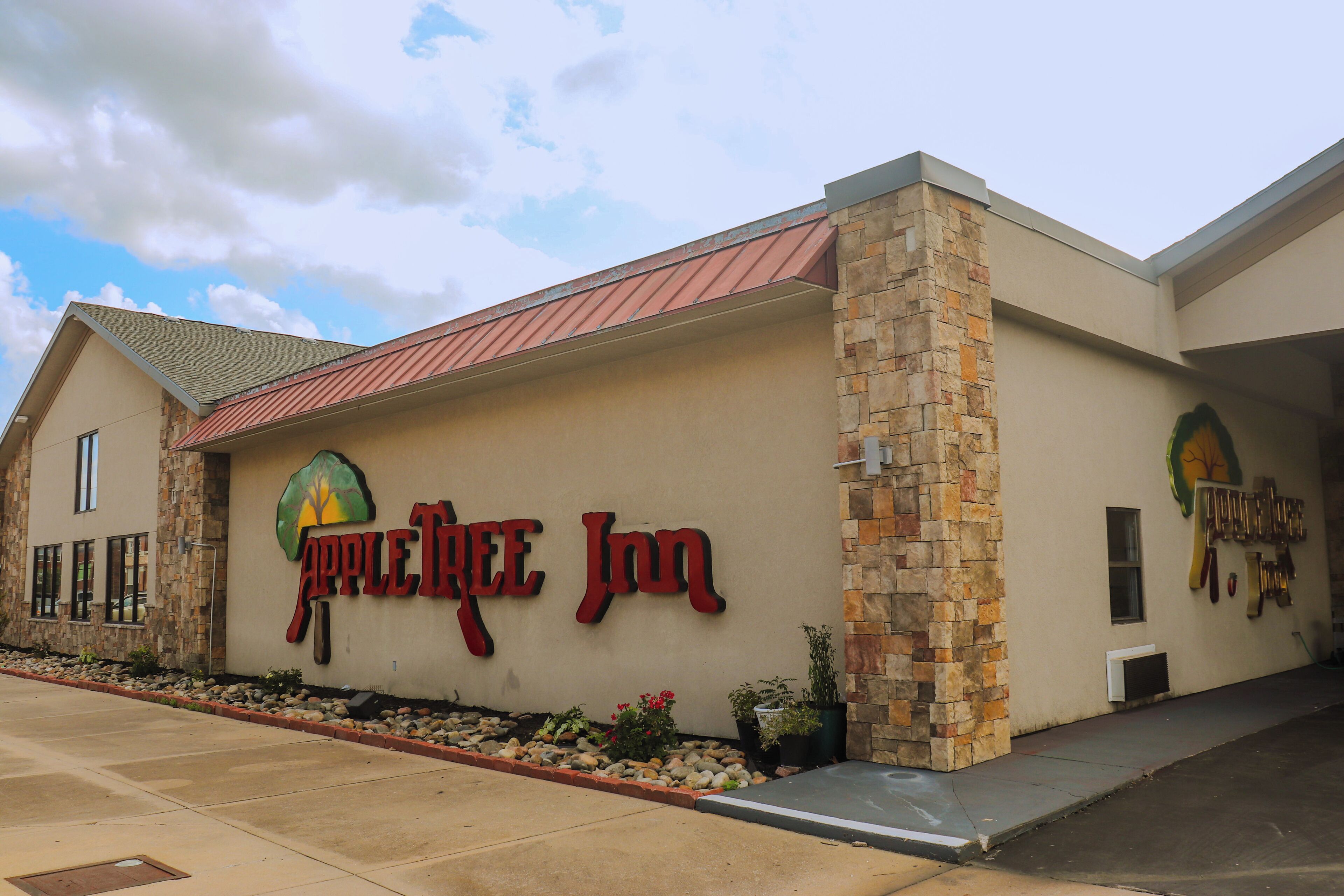 The exterior of the Apple Tree Inn, featuring a stone facade, a red roof, and a clear sky.