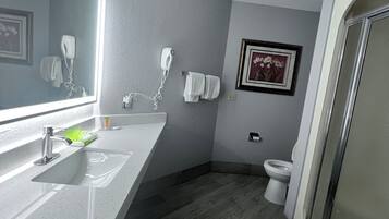 A bathroom with a white sink, a hairdryer, a toilet, and a shower.