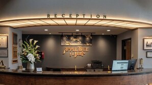 A reception area with a curved reception desk, a sign above it reading 'RECEPTION,' and a logo for 'AppleTree Inn' on the wall. - Apple Tree Inn and Suites (Independence)