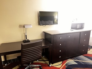Compact room with a desk, chair, flat-screen TV, and microwave.