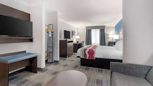 Ein Hotelzimmer mit Bett, Schreibtisch, Stuhl, Fernseher und Sitzbank.