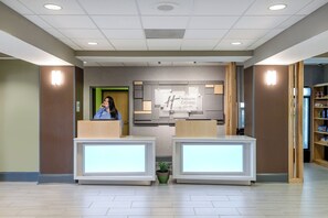 A reception area with a modern design, including a reception desk, a digital display, and a sign indicating the hotel name. - Holiday Inn Express & Suites Grenada by IHG (Grenada)