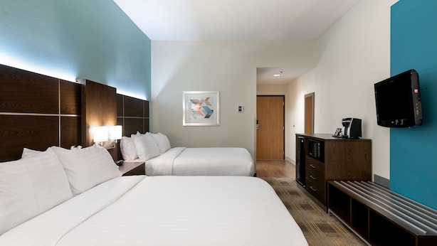 A hotel room with two beds, a desk with a lamp, a TV, and a painting on the wall. - Holiday Inn Express & Suites Grenada by IHG (Grenada)