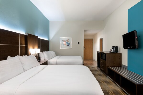 A hotel room with two beds, a desk with a lamp, a TV, and a painting on the wall. - Holiday Inn Express & Suites Grenada by IHG (Grenada)