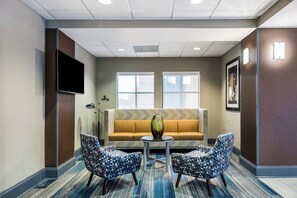 A lobby with a sofa, two patterned chairs, a small table, and a flat-screen TV on the wall. - Holiday Inn Express & Suites Grenada by IHG (Grenada)