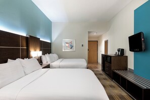 A hotel room with two beds, a desk with a lamp, a television, and a painting on the wall. - Holiday Inn Express & Suites Grenada by IHG (Grenada)