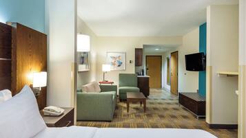 A hotel room with a bed, a desk, a chair, a television, and a door leading to another room.