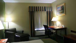 A hotel room with a bed, a desk, a chair, a lamp, and a window with curtains. - Holiday Inn Express & Suites Grenada by IHG (Grenada)