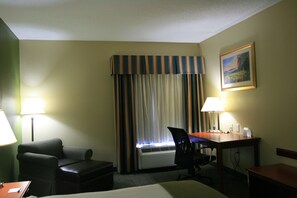 A hotel room with a bed, a desk, a chair, a lamp, and a window with curtains. - Holiday Inn Express & Suites Grenada by IHG (Grenada)