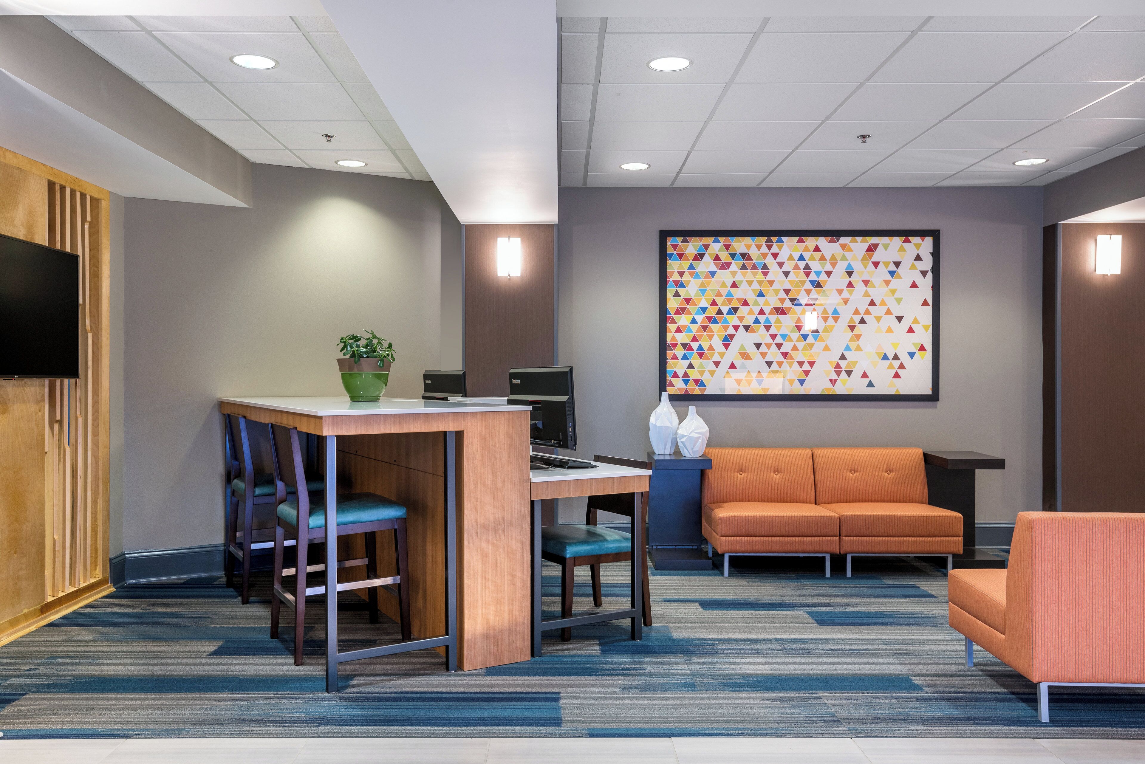 A modern office space with a desk, chairs, a sofa, and a large abstract painting on the wall.