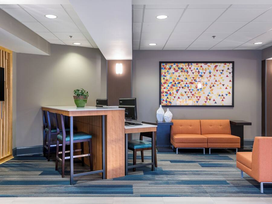 A modern office space with a desk, chairs, a sofa, and a large abstract painting on the wall.