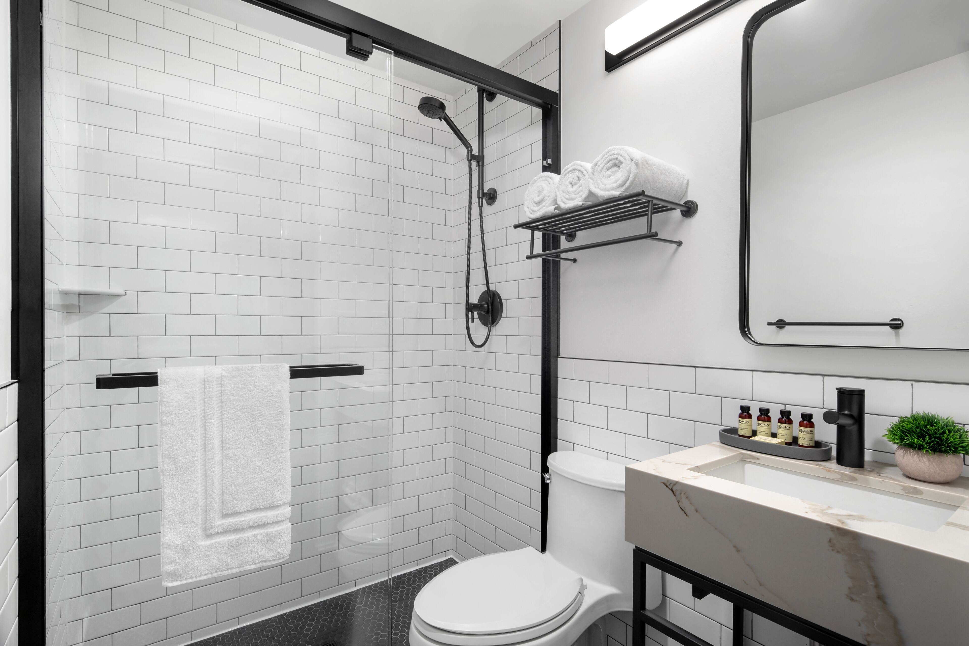 A modern bathroom with a shower, toilet, and sink.