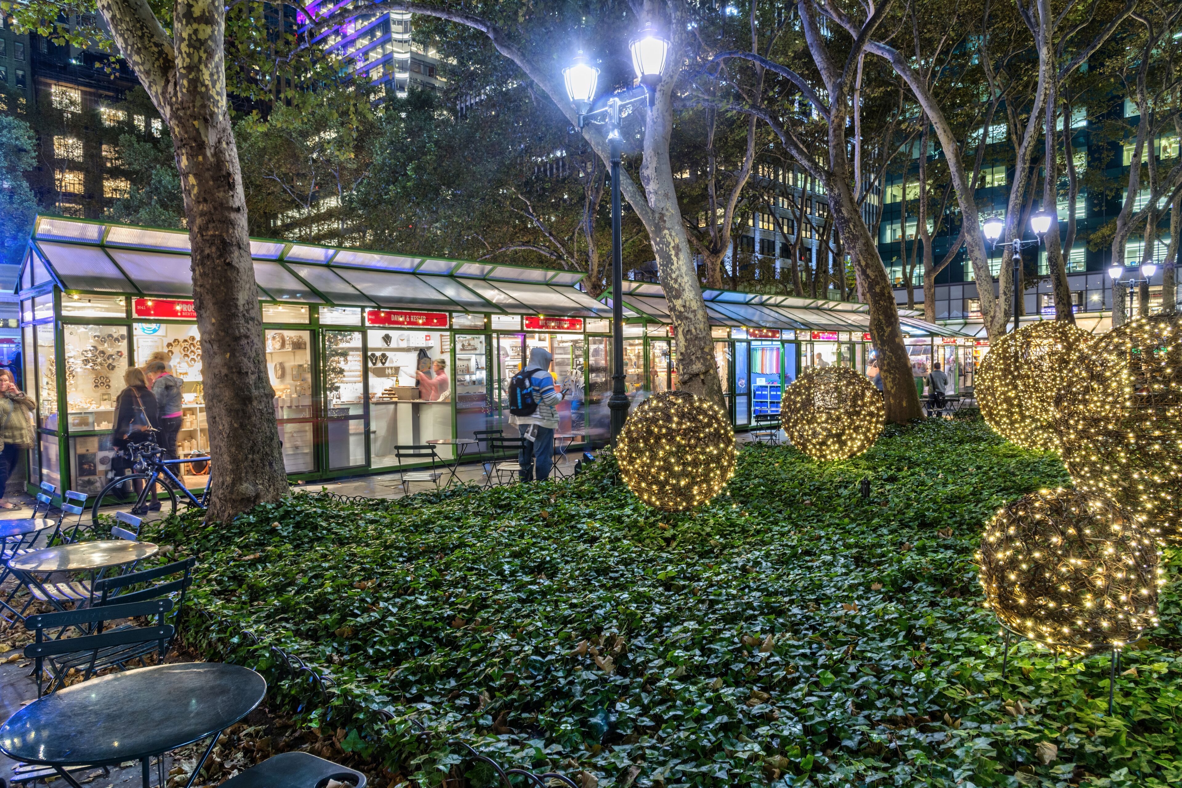 A public square with seating areas, a covered kiosk, and illuminated spherical decorations.