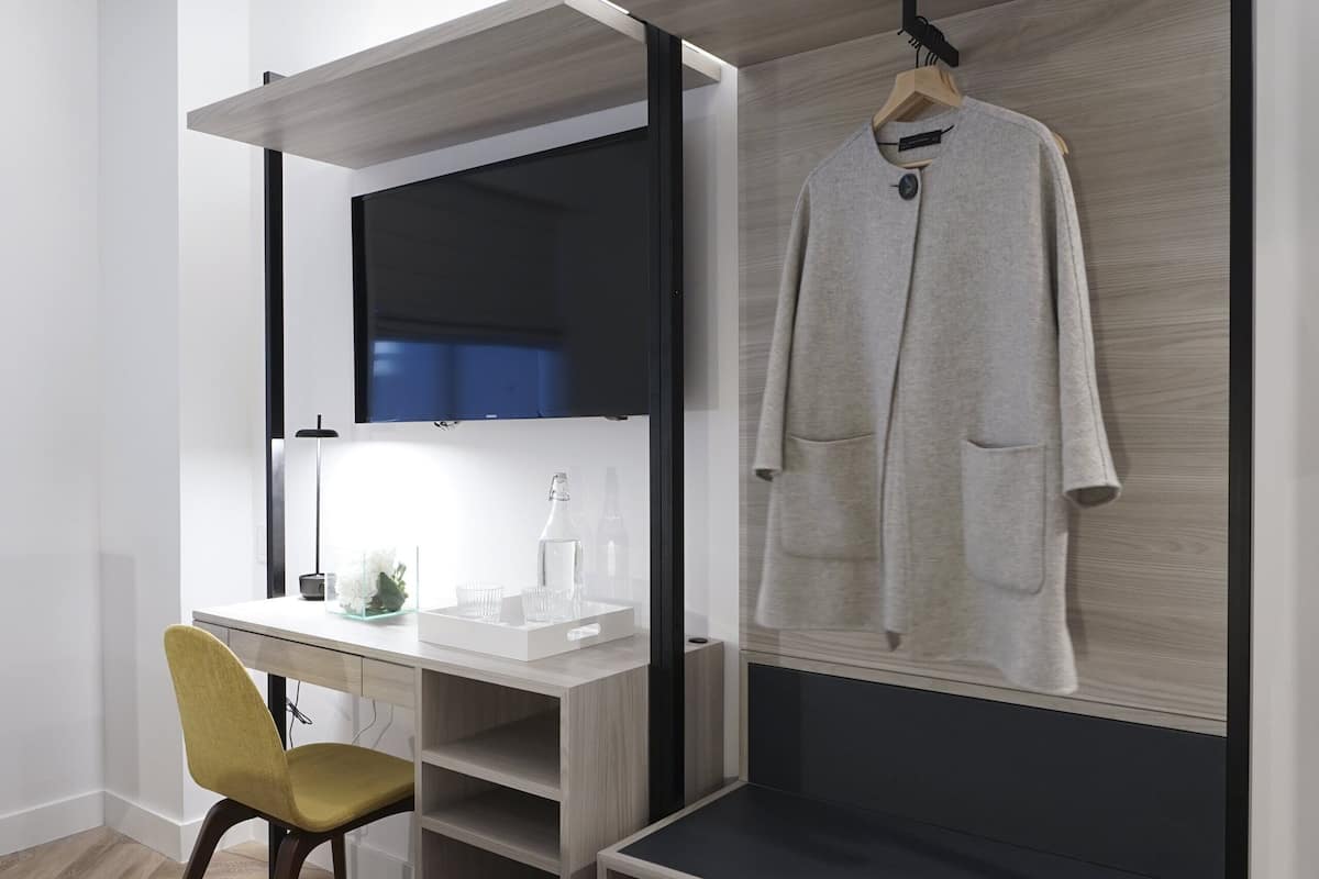 A modern room with a desk, chair, and a coat rack.