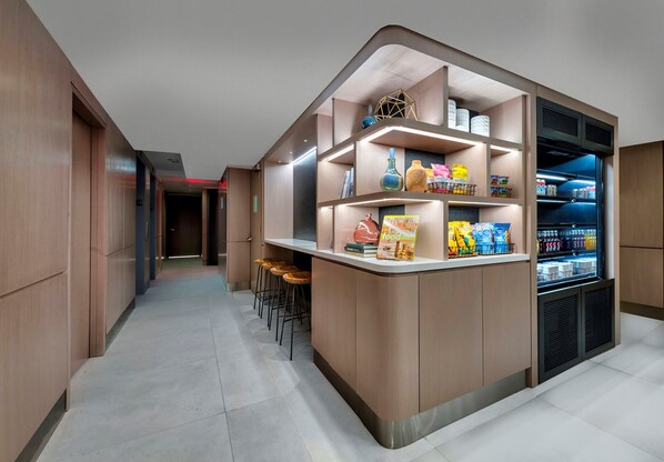 Una cocina moderna con refrigerador empotrado, una barra con taburetes y estantes con productos alimenticios.