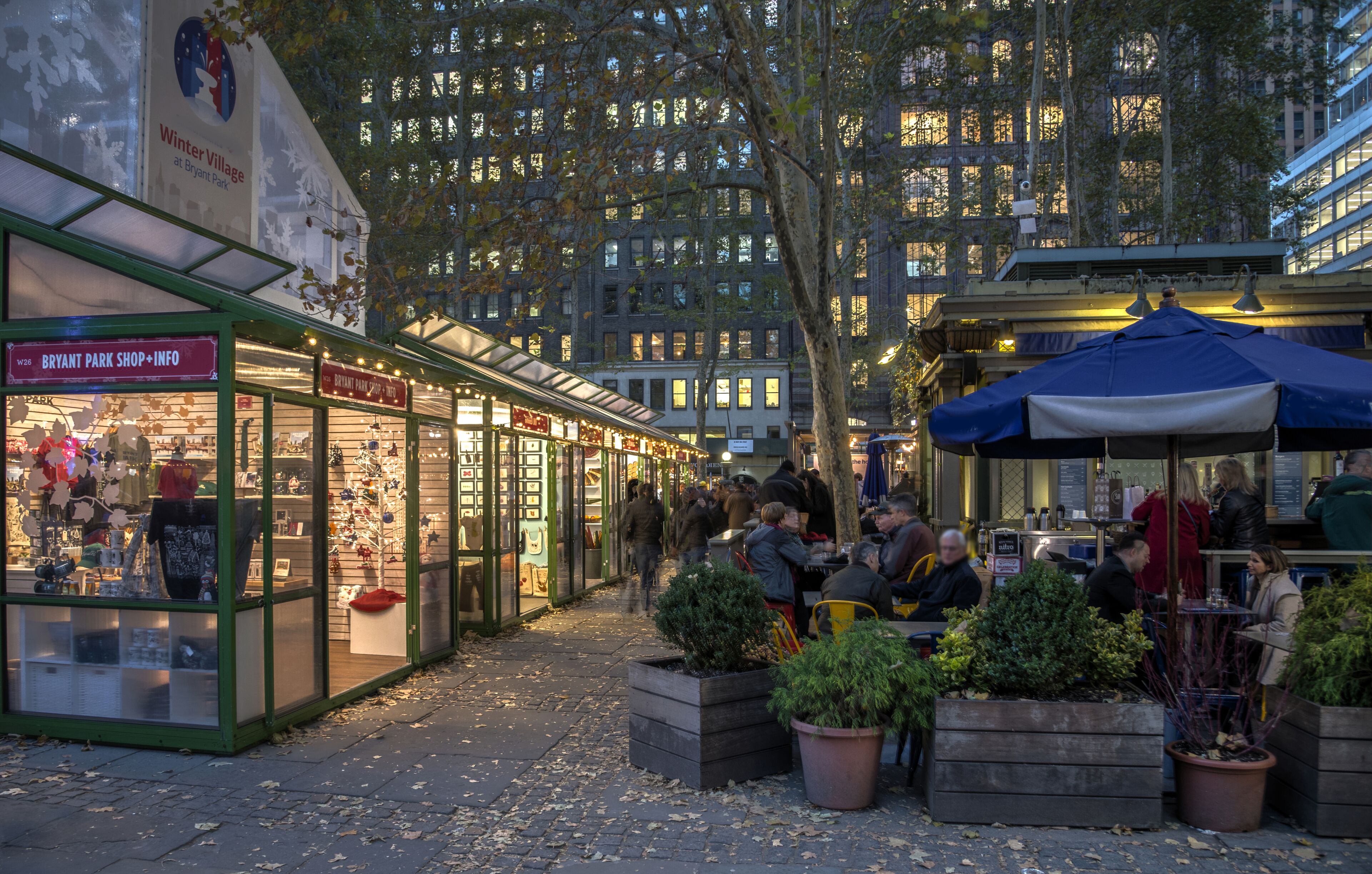A bustling outdoor market with shops and dining areas, surrounded by tall buildings.