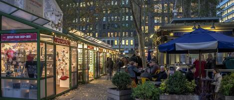 A bustling outdoor market with shops and dining areas, surrounded by tall buildings.