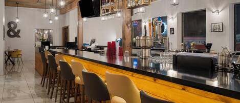 A bar area with a long counter, multiple stools, and a variety of bottles and glasses.