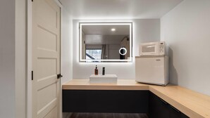 A modern kitchen with a built-in microwave, a sink with a mirror above it, and a wooden countertop. - The Hotel Pendleton, Trademark Collection by Wyndham (Pendleton)