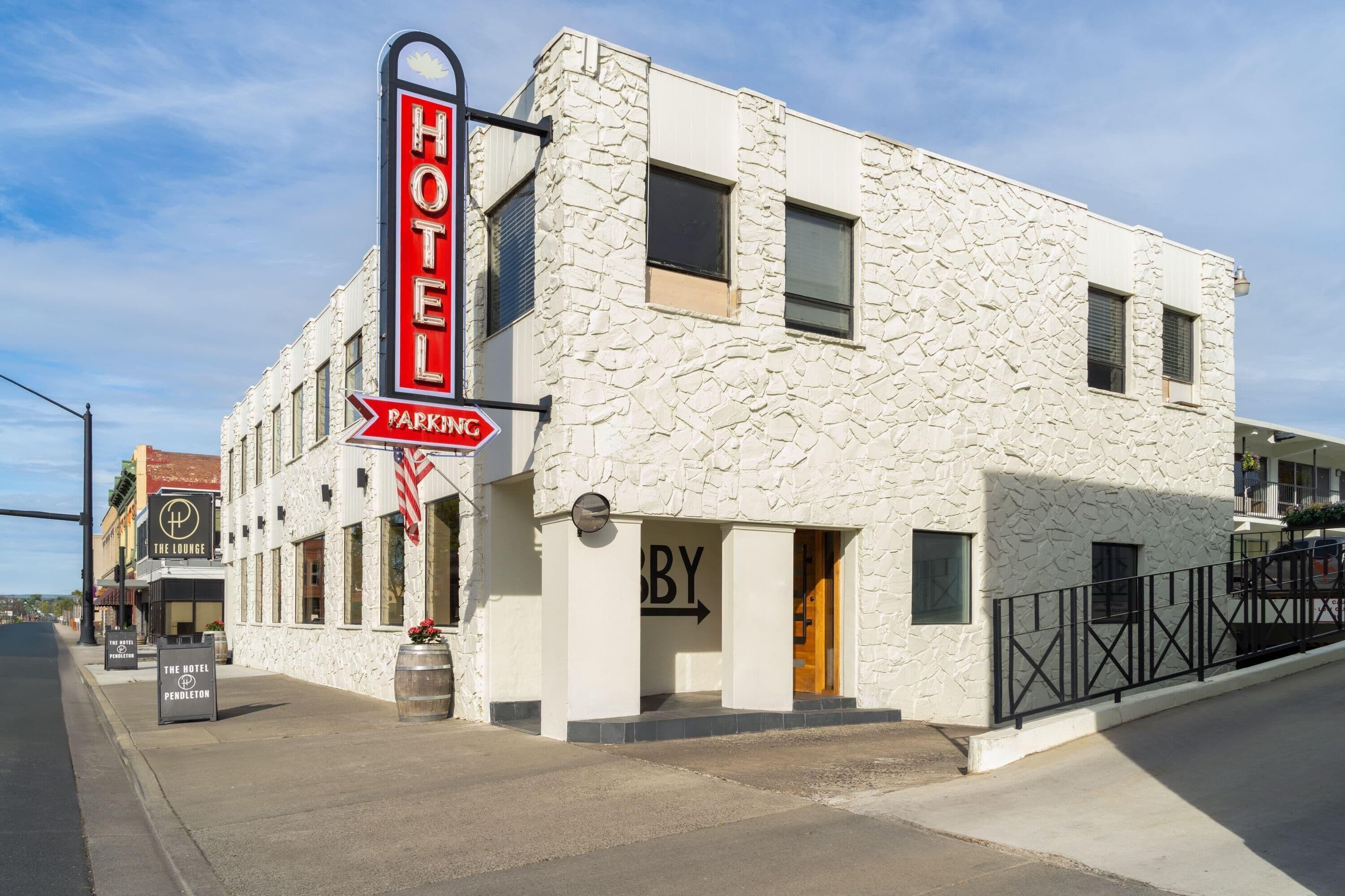 A hotel with a stone facade, a neon sign, and a parking sign.