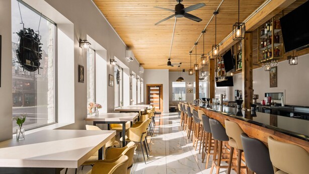 A modern bar area with high ceilings, wooden beams, and a polished marble floor. - The Hotel Pendleton, Trademark Collection by Wyndham (Pendleton)
