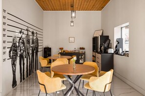 A dining area with a round table and yellow chairs, a kitchen with a black countertop, and a wall-mounted height chart.