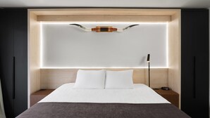 A modern bedroom with a bed, bedside tables, and a headboard with integrated lighting. - The Hotel Pendleton, Trademark Collection by Wyndham (Pendleton)
