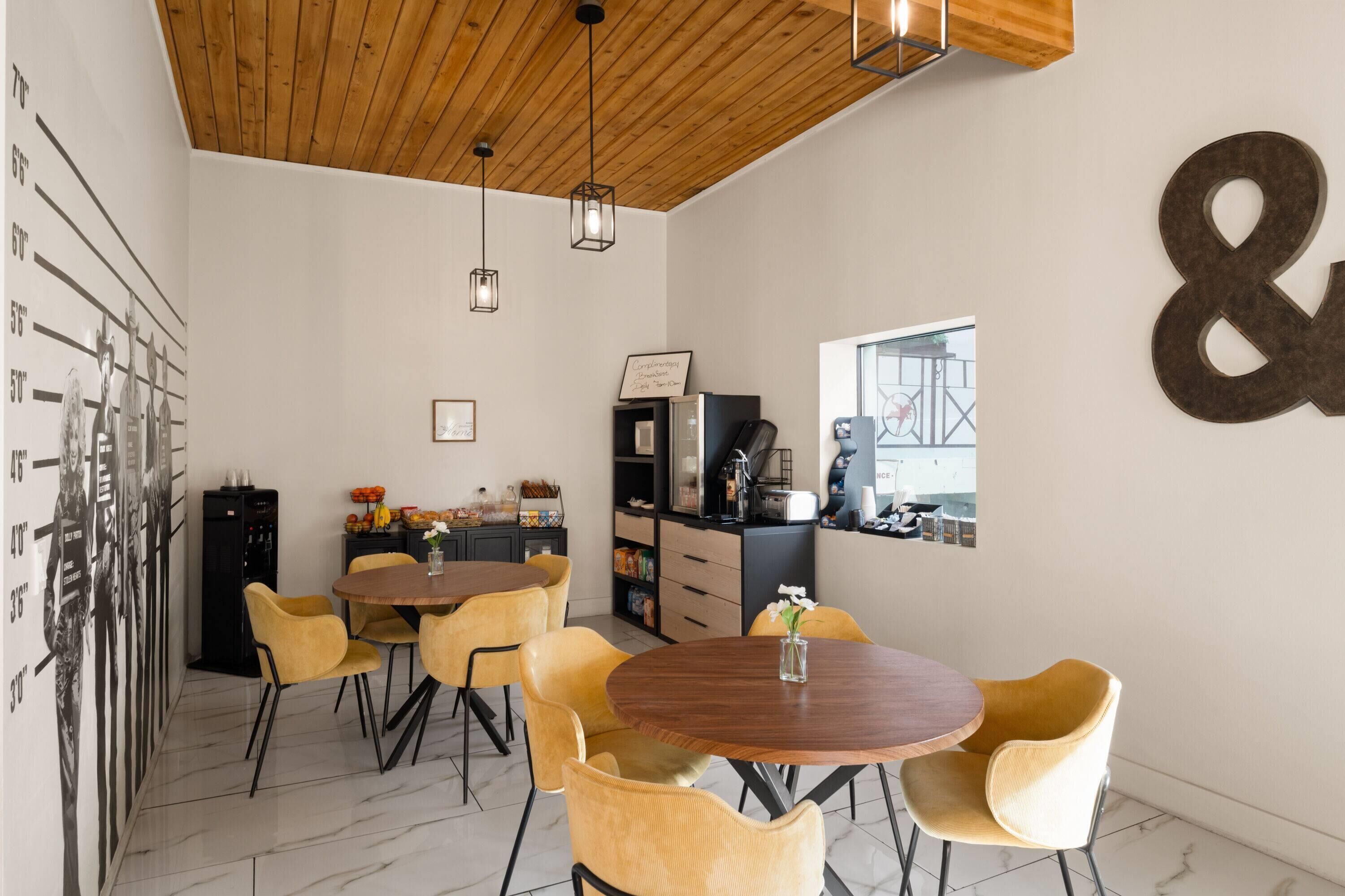 Eine moderne Küche mit Holzboden, ein Essbereich mit gelben Stühlen und ein großes '&'-Zeichen an der Wand.
