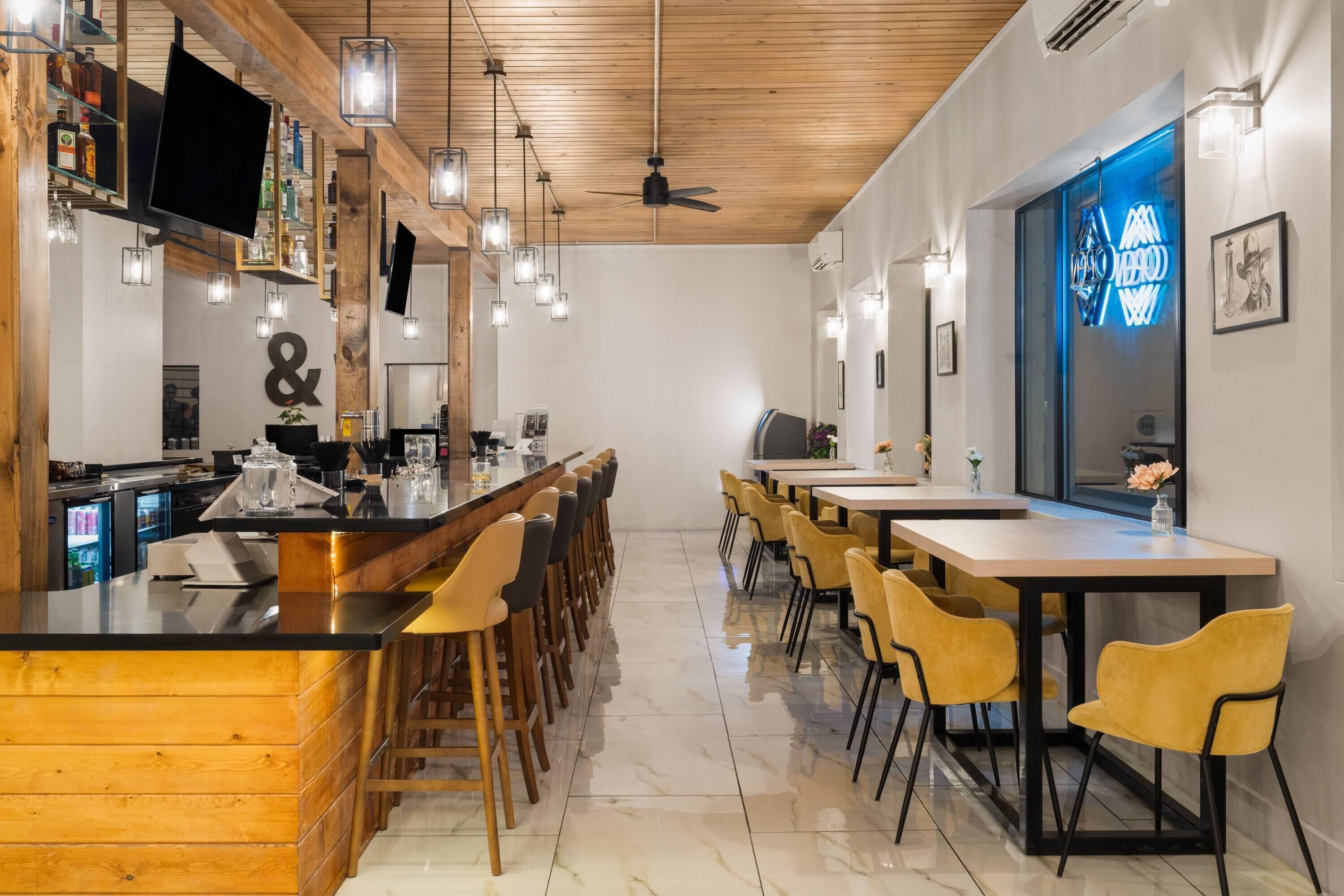 Eine Bar mit Holztresen, hängenden Lampen und einem Deckenventilator.