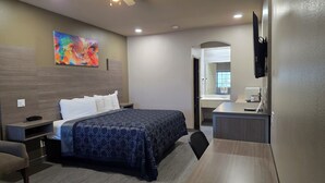Una habitación de hotel con cama, mesita de noche, silla, escritorio y televisor.