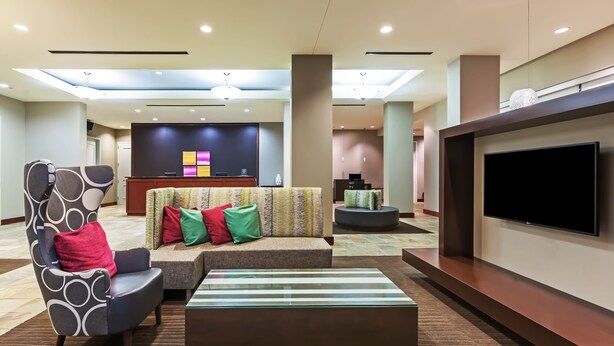 A modern hotel lobby with a reception desk, seating area, and a large flat-screen TV. - Residence Inn Houston West-Energy Corridor (Houston)