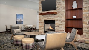 A hotel lobby with a fireplace, seating area, and a television mounted on the wall. - Residence Inn Houston West-Energy Corridor (Houston)