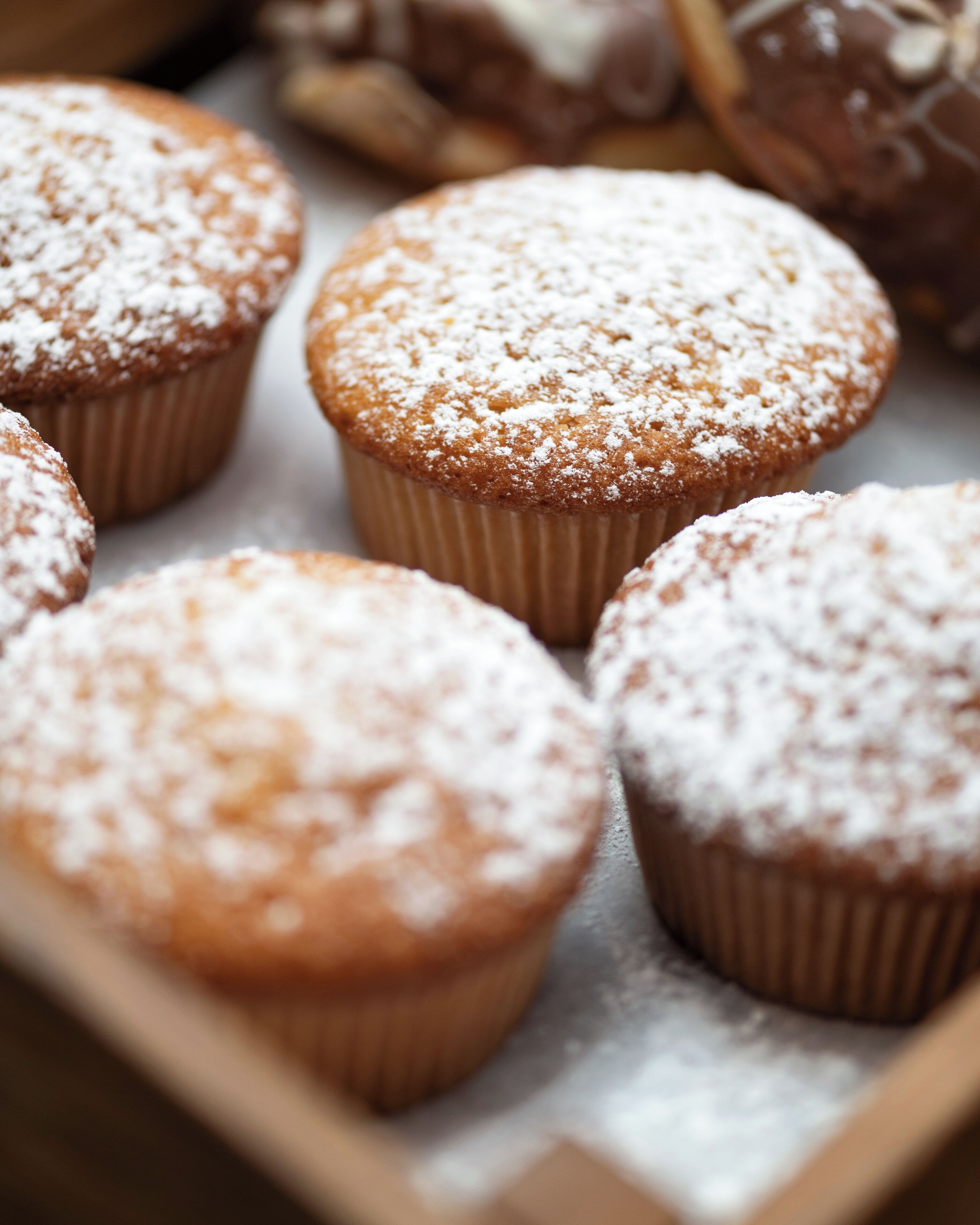 A tray of muffins with powdered sugar.