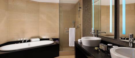 Un baño moderno con dos lavamanos, una bañera y una ducha con mampara de vidrio.