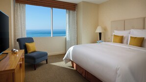 A hotel room with a large bed, a TV, a desk, and a view of the ocean. - Renaissance by Sulo (Aktau)