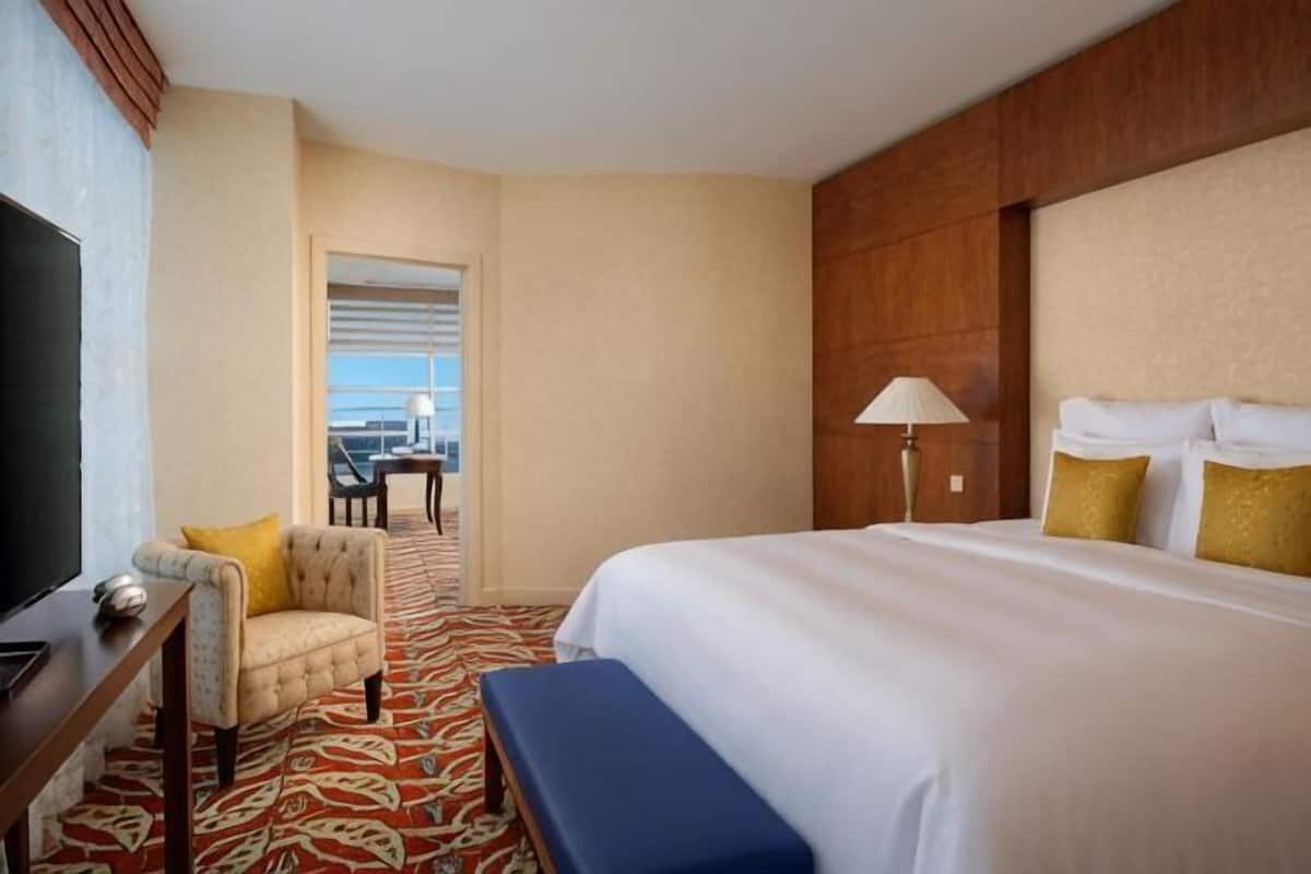 Ein Hotelzimmer mit Bett, Schreibtisch mit Fernseher, Stuhl, Lampe und Blick nach draußen.