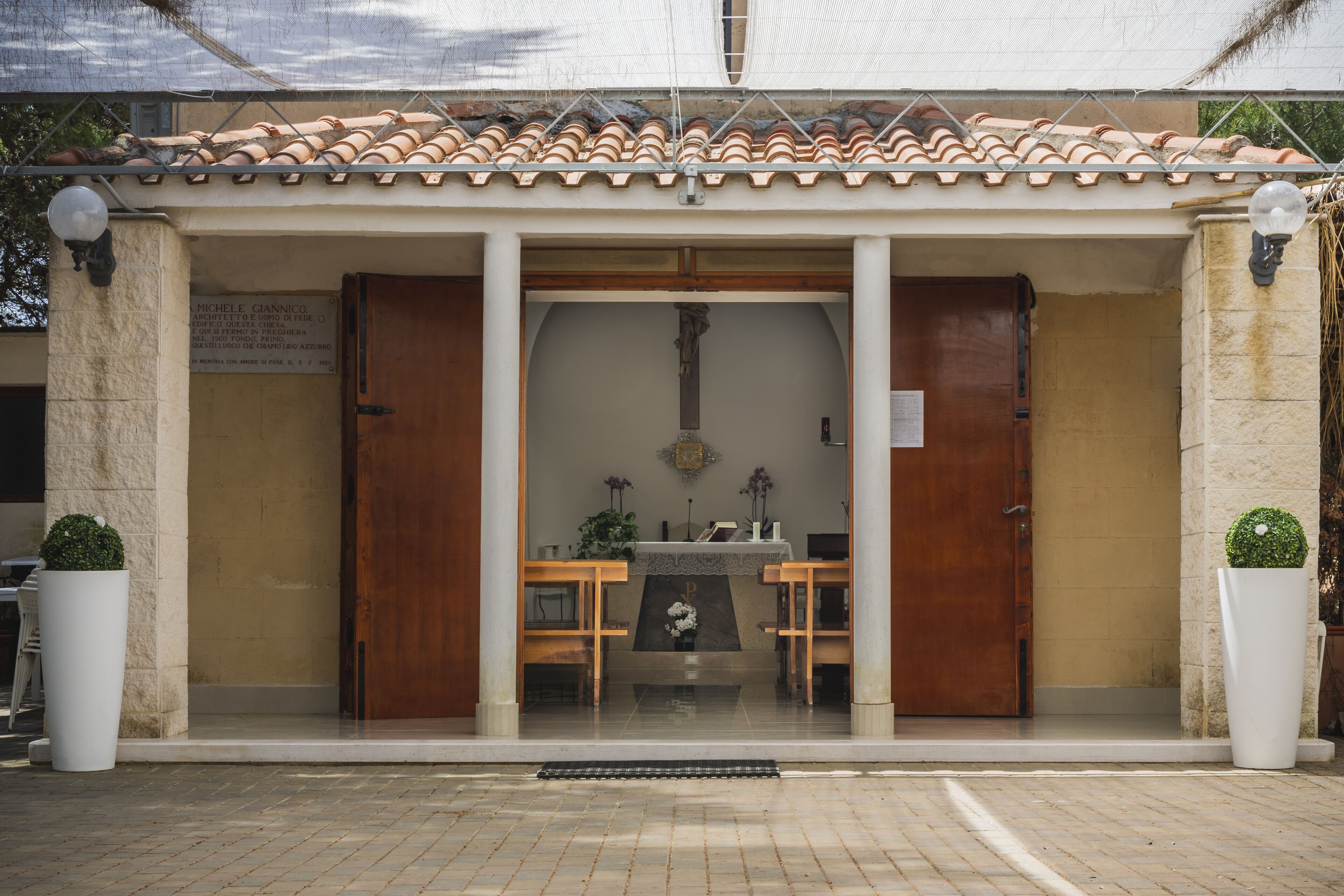 A building with a tiled roof, a wooden door, and a small altar with a statue.