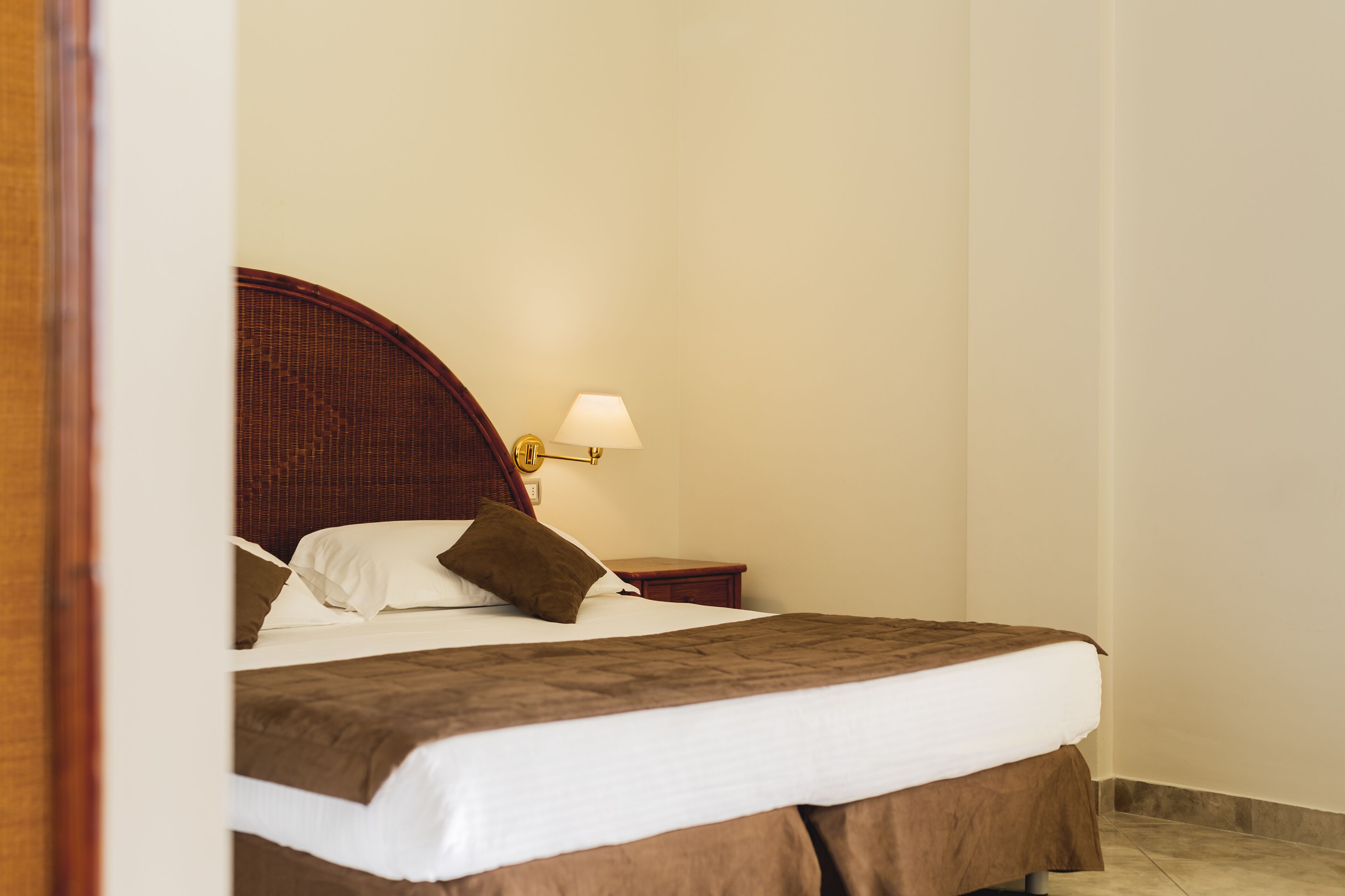 Ein ordentlich gemachtes Bett mit braunem Kopfteil, weißen Laken und einer braunen Tagesdecke.