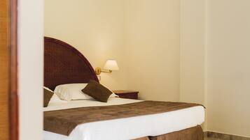 Ein ordentlich gemachtes Bett mit braunem Kopfteil, weißen Laken und einer braunen Tagesdecke.