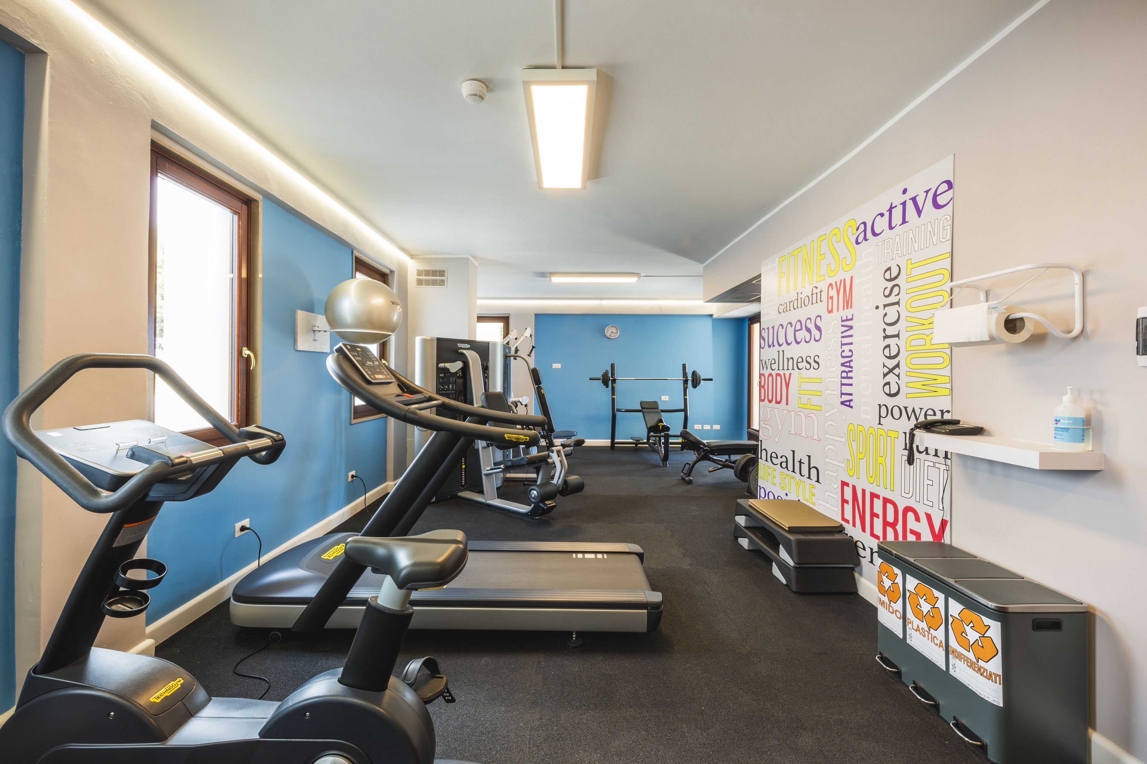 Un gimnasio con cintas de correr, elípticas y bancos de pesas.