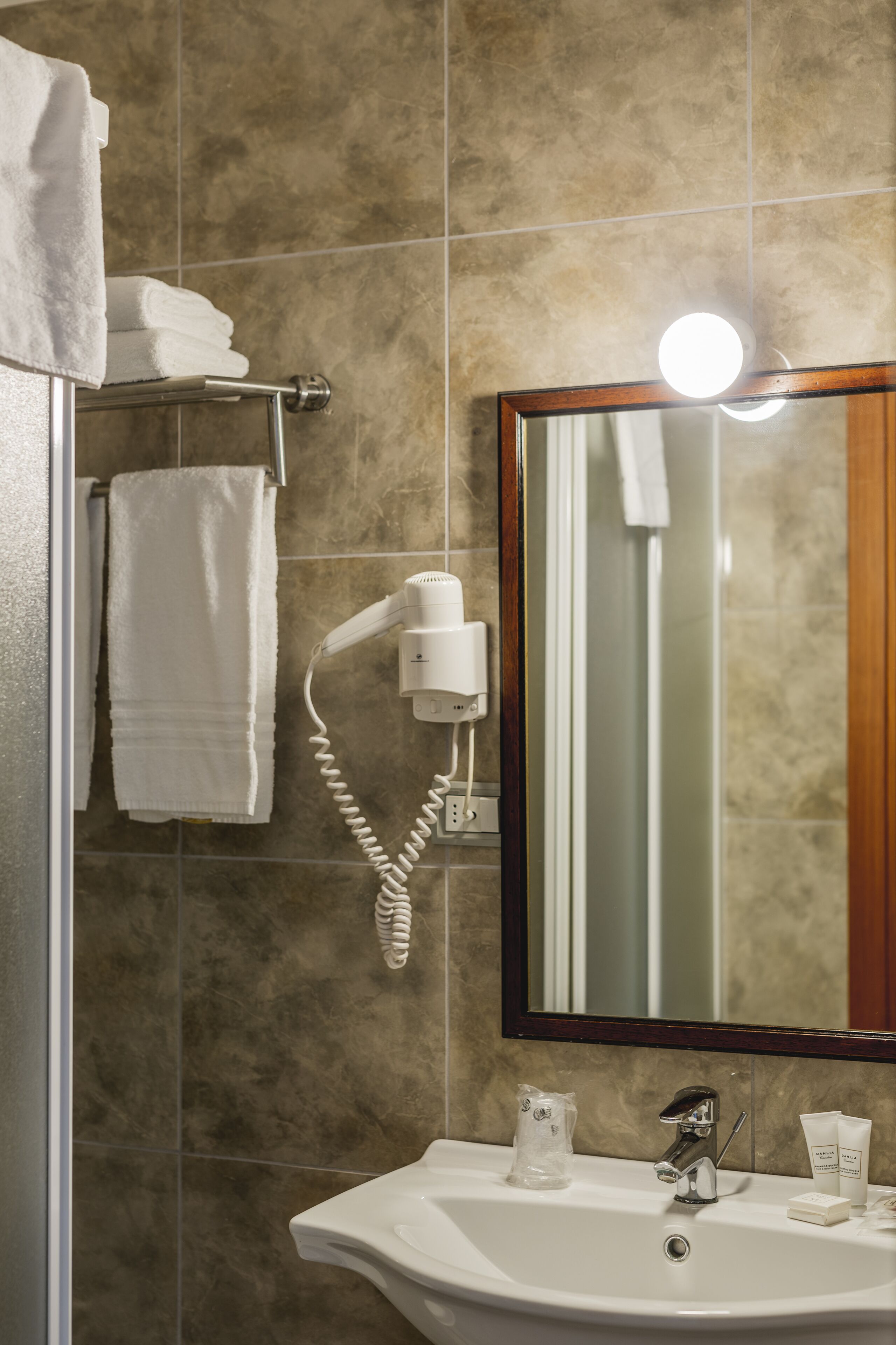 A bathroom with a sink, a hairdryer, and a mirror.