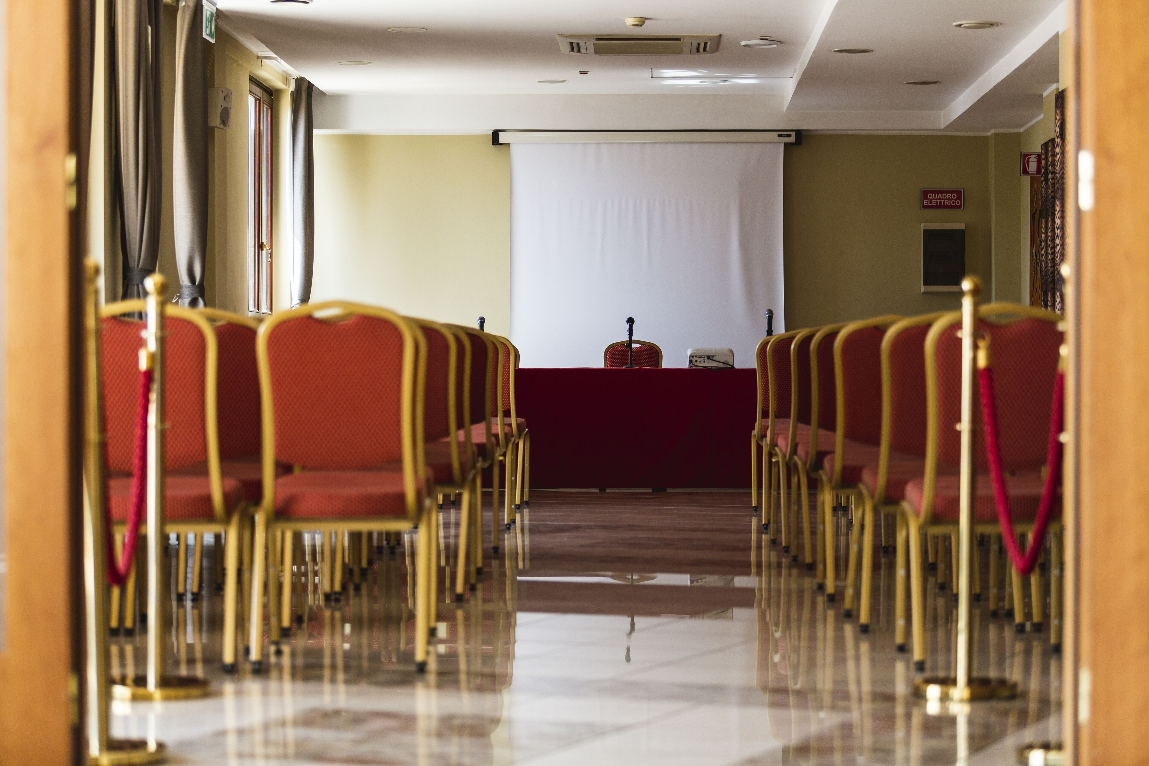 A conference room with rows of red chairs and a podium at the front.
