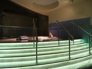 A person relaxing on a set of stairs with a view of a building and a tiled wall. - The Sebel Sydney Chatswood (Chatswood)