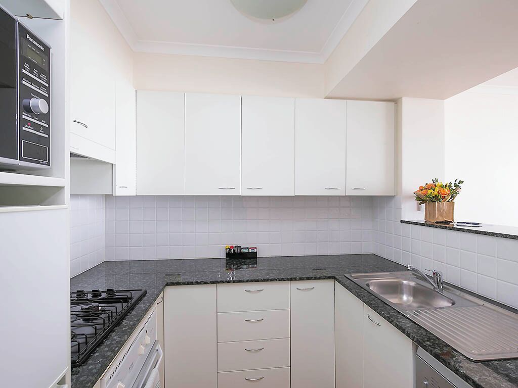A modern kitchen with white cabinets, a gas stove, a sink, and a countertop.