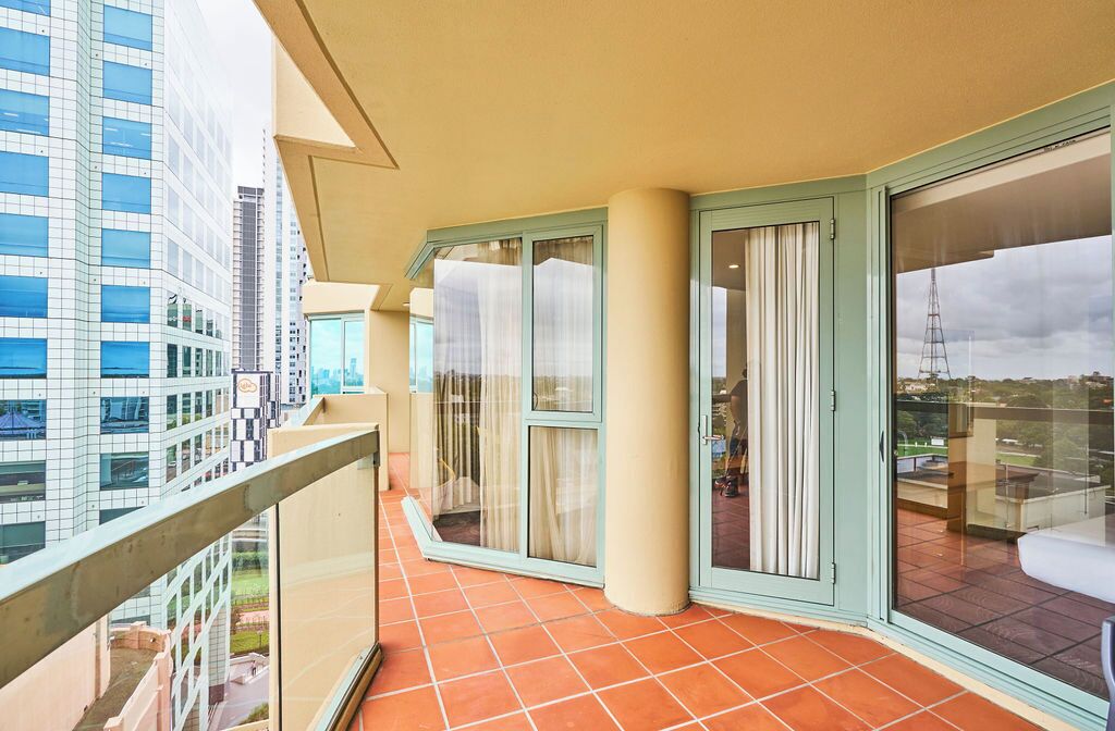A balcony with a tiled floor, glass doors, and a view of a cityscape.