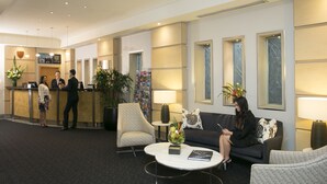A modern hotel lobby with a reception desk, seating area, and large windows. - The Sebel Sydney Chatswood (Chatswood)